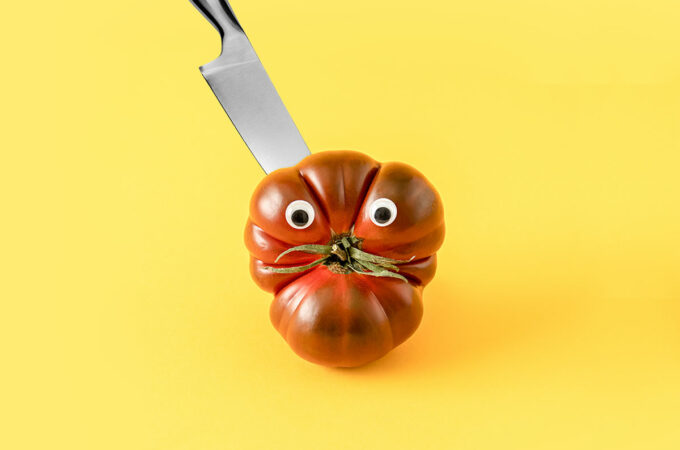 odd shaped tomato with google eyes with knife sticking out