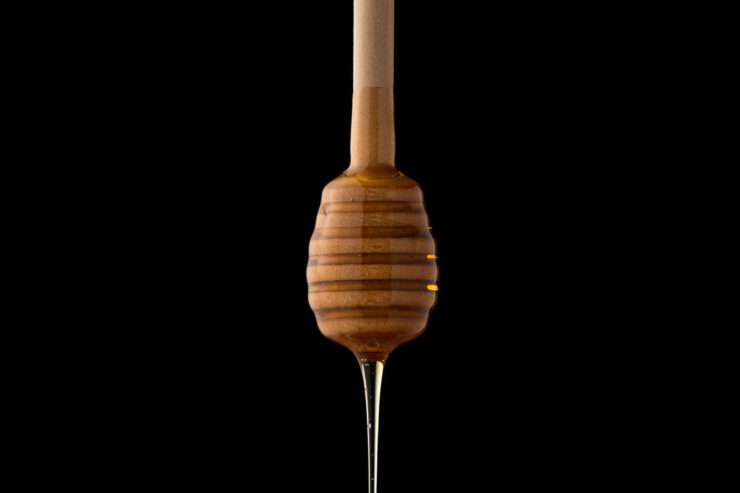 honey wand against black background dripping honey