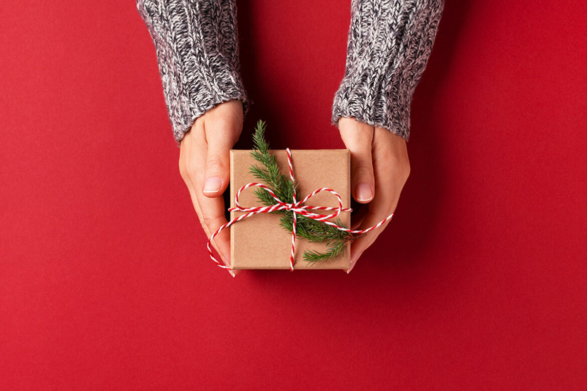 hands holding a square holiday gift on red background