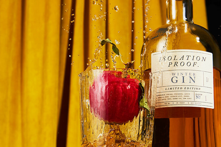 an apple splashing into a rocks glass of isolation proof gin