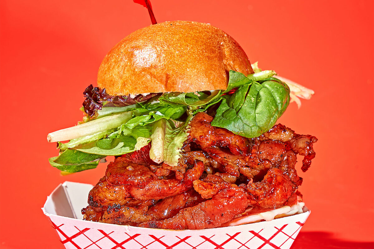 a hot chicken sandwich piled high against a red background