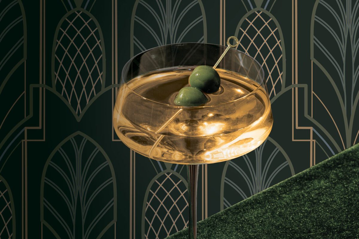 an aquavit martini with two olives against an art deco pineapple patterned background