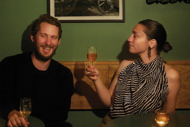 two people sharing wine in a dimly lit green bar