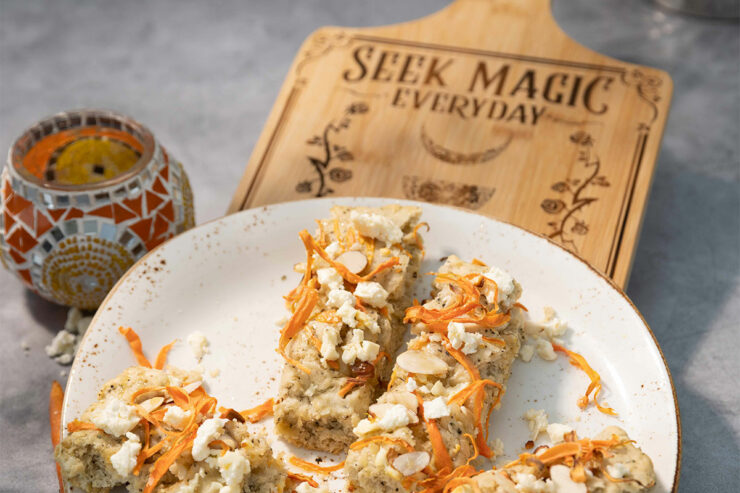 carrot feta focaccia on a white plate near a wooden cutting board that says Seek Magic Every Day